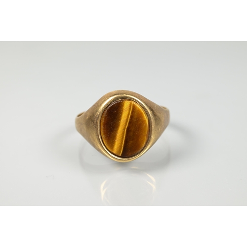 191 - A signet ring set oval tiger's eye in 9ct yellow gold, size S 1/2