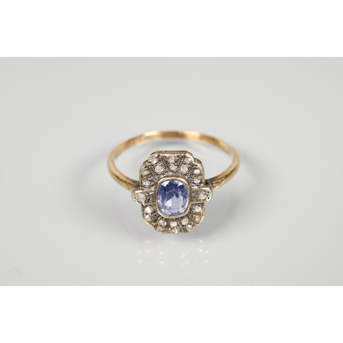 192 - An antique plaque ring, the central pale blue oval sapphire surrounded by rose cut diamonds in milgr... 