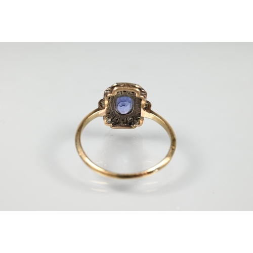 192 - An antique plaque ring, the central pale blue oval sapphire surrounded by rose cut diamonds in milgr... 