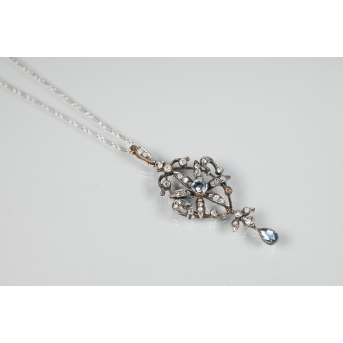 211 - An Edwardian foliate and scroll pendant, the open flower set overall with diamonds and with a centra... 