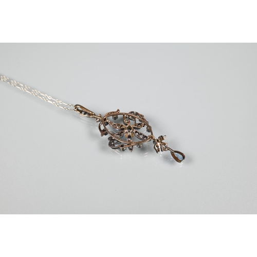 211 - An Edwardian foliate and scroll pendant, the open flower set overall with diamonds and with a centra... 