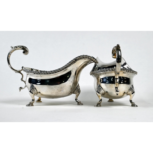 22 - A pair of silver sauce-boats in the Georgian manner, with gadrooned rims and scroll handles, on hoof... 