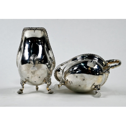 22 - A pair of silver sauce-boats in the Georgian manner, with gadrooned rims and scroll handles, on hoof... 
