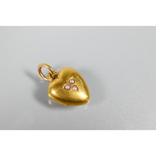 240 - A Victorian 15ct heart shaped locket, set with three seed pearls to front and opening to reveal hair... 