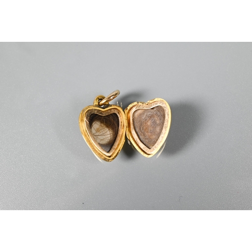 240 - A Victorian 15ct heart shaped locket, set with three seed pearls to front and opening to reveal hair... 