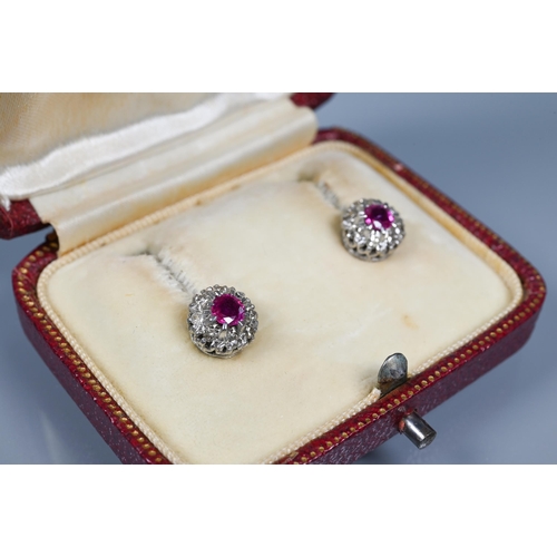 244 - A pair of white stone and ruby cluster earrings, the central circular ruby surrounded by eight white... 