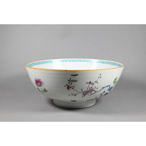 298 - An 18th century Chinese famille rose punch bowl painted with large blossoming peonies in a fenced ga... 