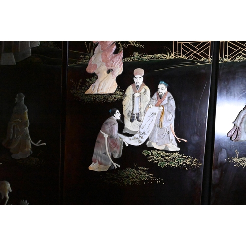 327A - An early 20th century Chinese lacquered four panel screen painted and gilded with idyllic landscapes... 