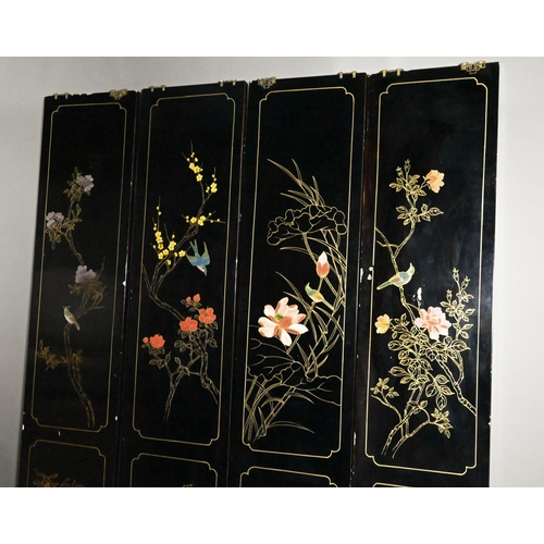 327A - An early 20th century Chinese lacquered four panel screen painted and gilded with idyllic landscapes... 