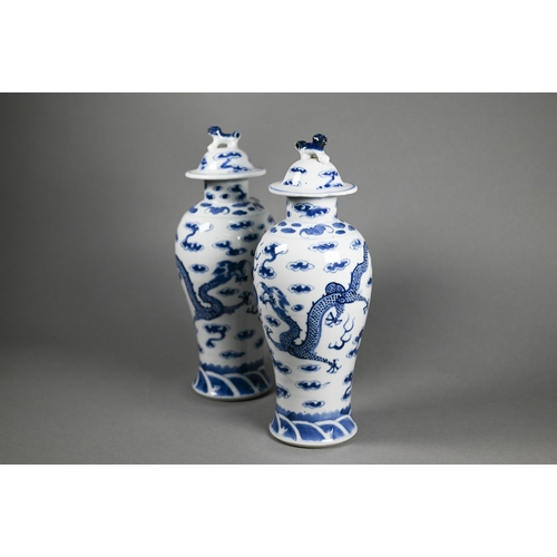 351 - A pair of 19th century Chinese blue and white baluster vases with domed covers surmounted by guardia... 