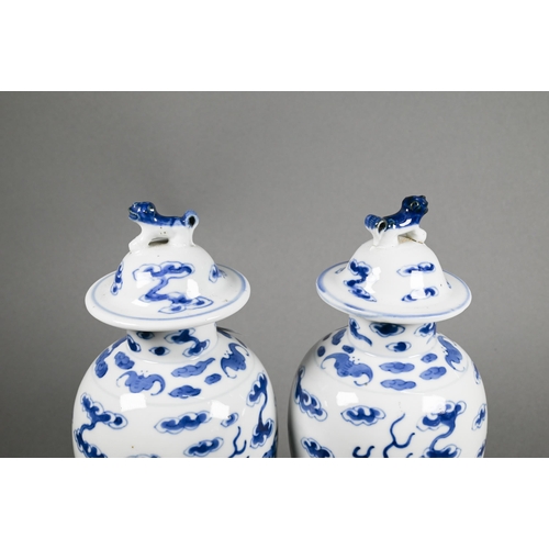 351 - A pair of 19th century Chinese blue and white baluster vases with domed covers surmounted by guardia... 