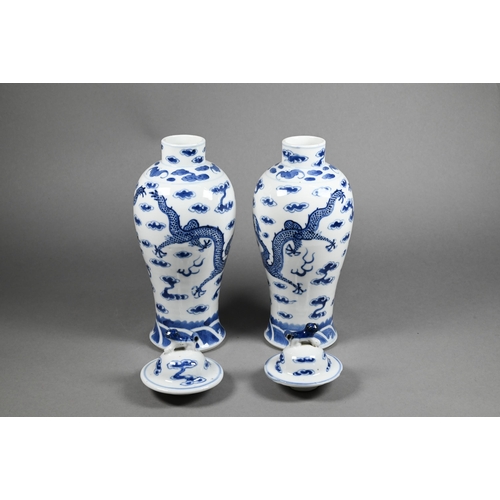 351 - A pair of 19th century Chinese blue and white baluster vases with domed covers surmounted by guardia... 