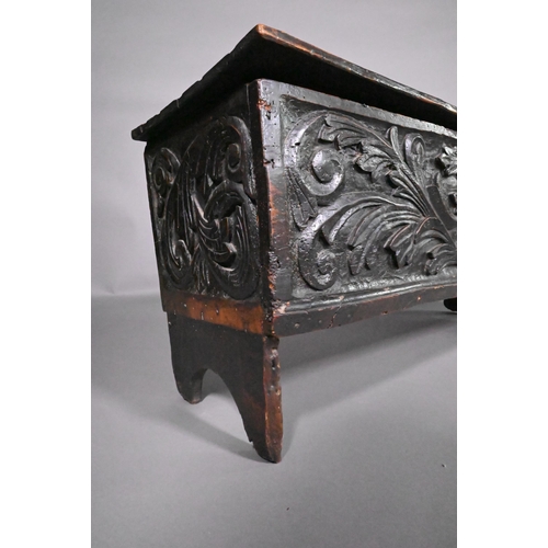 838 - A 17th century oak/elm six plank coffer, the hinged top with carved edge over bold leaf carved front... 