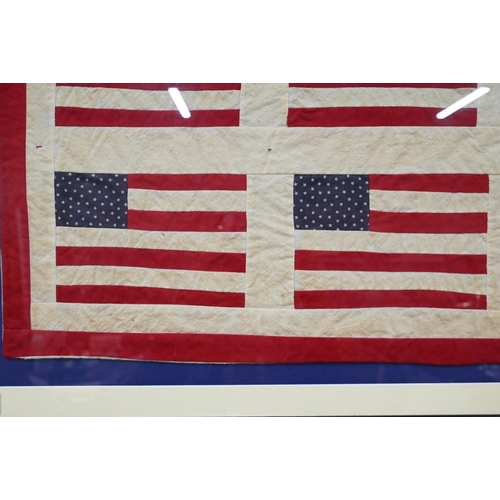 964 - A small vintage quilt, worked with stylised United States flags, 83 x 66 cm, mounted, framed and gla... 