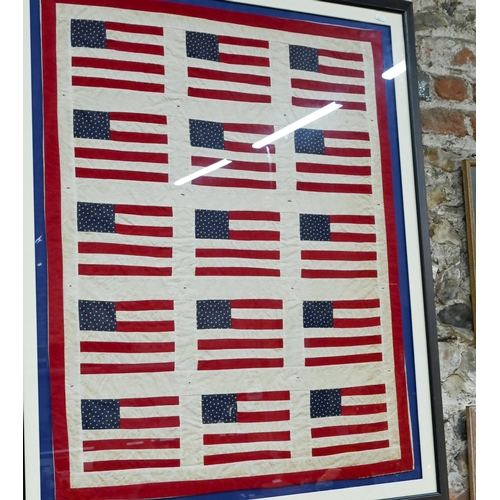 964 - A small vintage quilt, worked with stylised United States flags, 83 x 66 cm, mounted, framed and gla... 