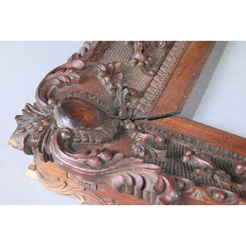 993 - An antique Anglo-Indian padouk wood picture frame, finely carved in the Rococo manner with floral an... 