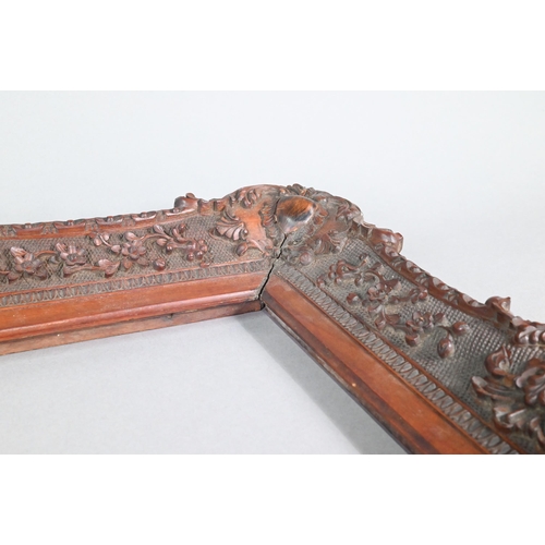 993 - An antique Anglo-Indian padouk wood picture frame, finely carved in the Rococo manner with floral an... 