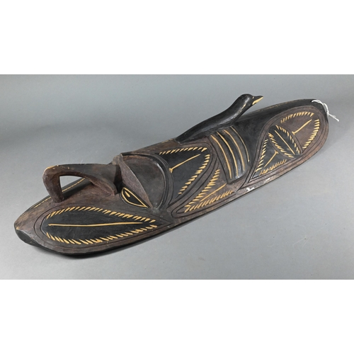 998 - A Papua New Guinea tribal carved wood shield, worked with a mask with prominent nose below a bird, 7... 