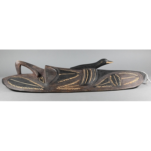 998 - A Papua New Guinea tribal carved wood shield, worked with a mask with prominent nose below a bird, 7... 