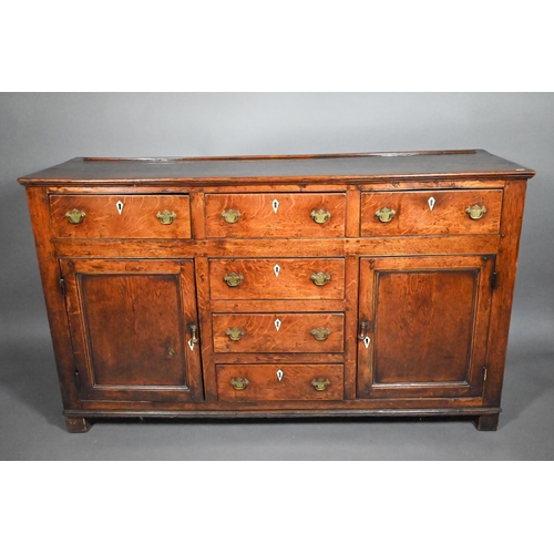 832 - A George III oak low dresser, with an arrangement of six drawers and two cupboards, with bone escutc... 