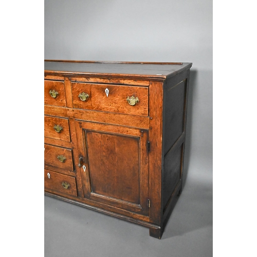 832 - A George III oak low dresser, with an arrangement of six drawers and two cupboards, with bone escutc... 