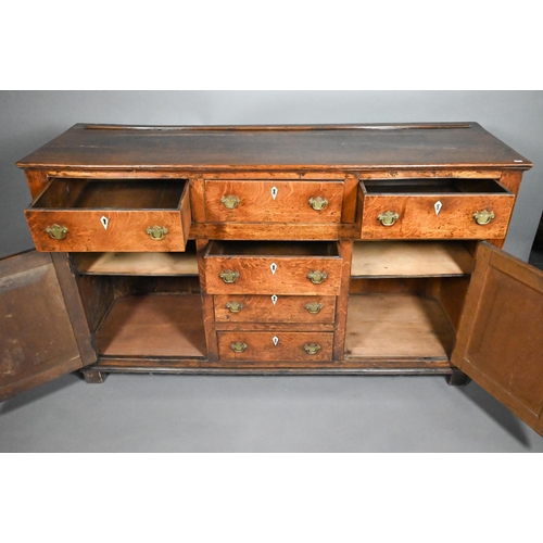 832 - A George III oak low dresser, with an arrangement of six drawers and two cupboards, with bone escutc... 