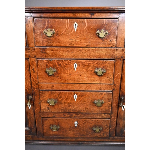 832 - A George III oak low dresser, with an arrangement of six drawers and two cupboards, with bone escutc... 