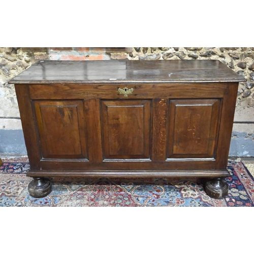 841 - A large Georgian oak coffer, the wide two plank top over a triple fielded panel front, raised on bun... 