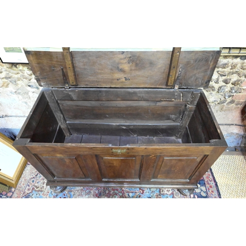 841 - A large Georgian oak coffer, the wide two plank top over a triple fielded panel front, raised on bun... 