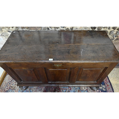 841 - A large Georgian oak coffer, the wide two plank top over a triple fielded panel front, raised on bun... 