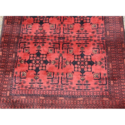 901 - A vintage Afghan rug, the red/brown ground with stylised geometric panels, 194 cm x 124 cm