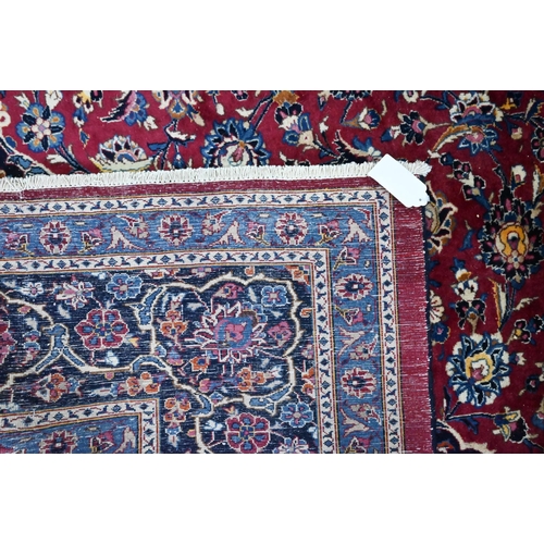 914 - A Persian Meshed carpet, the red/blue ground centred by a floral medallion, 373 cm x 300 cm