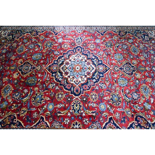 915 - A Persian Kashan carpet, the red ground centred by a blue floral diamond, 360 cm x 250 cm