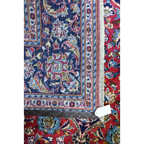 915 - A Persian Kashan carpet, the red ground centred by a blue floral diamond, 360 cm x 250 cm