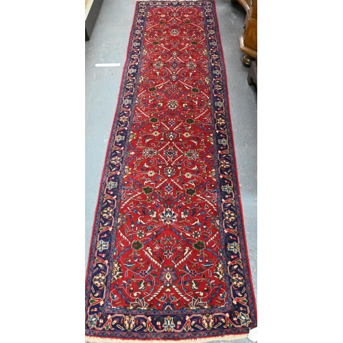 918 - A Persian Sarouk runner, the red ground with repeating design of interlinked floral vines, 307 cm x ... 