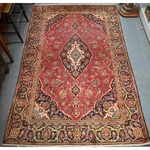 919 - A Persian Kashan rug, the soft red ground centred by a dark blue diamond medallion, 206 cm x 130 cm