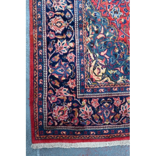 923 - A Persian Sarouk carpet, the red ground centred by a blue ground medallion radiating floral vines, 3... 