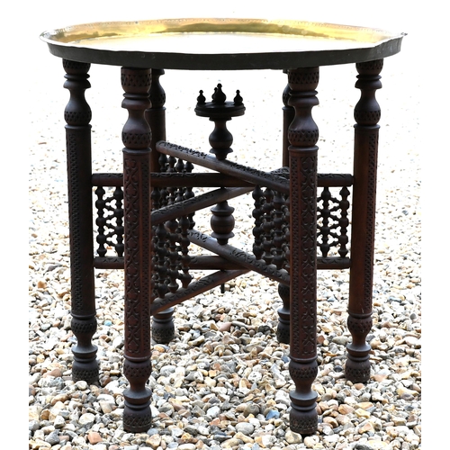 377 - An antique Ottoman circular brass top table, on a carved folding base, 58 cm dia. x 58 cm h