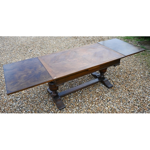 414 - An oak draw-leaf dining table raised on baluster turned ends united by a centre stretcher, 135 (247 ... 