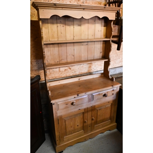 442 - A pine cottage dresser, the three tier rack over two drawers and pair of cupboards on a wavy plinth ... 