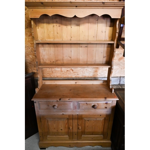 442 - A pine cottage dresser, the three tier rack over two drawers and pair of cupboards on a wavy plinth ... 