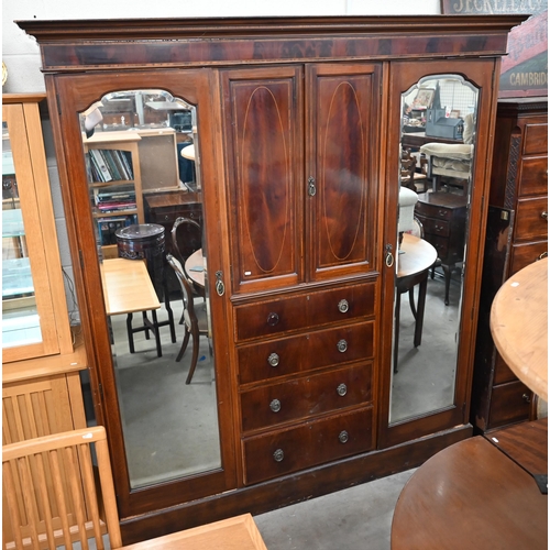 486 - A Victorian inlaid mahogany triple wardrobe with mirrored doors flanking cupboard and four drawers, ... 