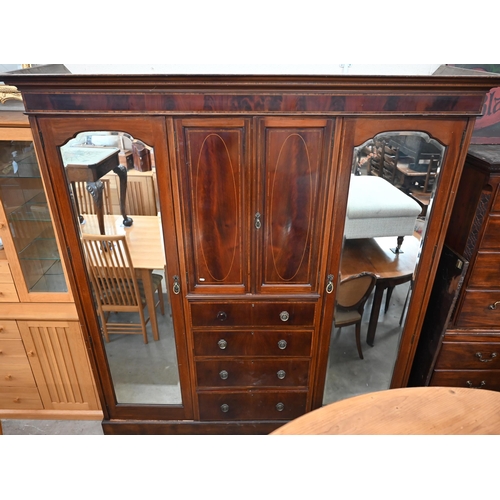 486 - A Victorian inlaid mahogany triple wardrobe with mirrored doors flanking cupboard and four drawers, ... 