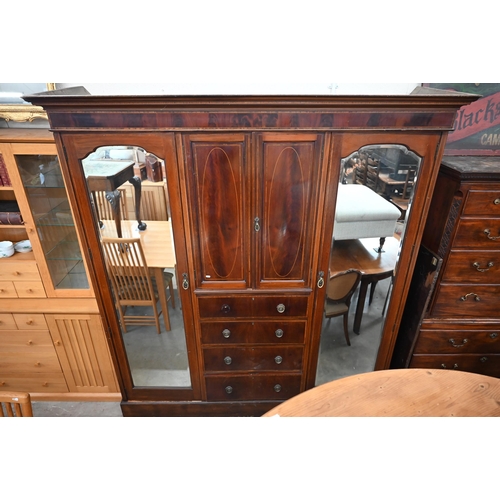 486 - A Victorian inlaid mahogany triple wardrobe with mirrored doors flanking cupboard and four drawers, ... 