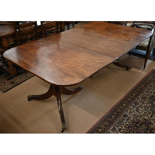 501 - A Georgian mahogany twin pedestal dining table with leaf, on turned pillars and tripod supprts, with... 