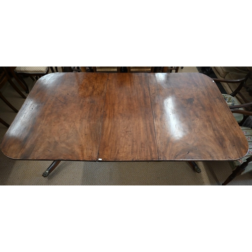 501 - A Georgian mahogany twin pedestal dining table with leaf, on turned pillars and tripod supprts, with... 