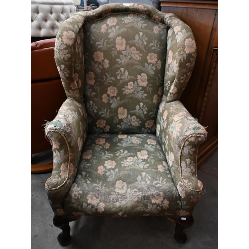 514 - An upholstered Victorian wing armchair raised on mahogany legs united by an 'H' stretcher, stamped '... 