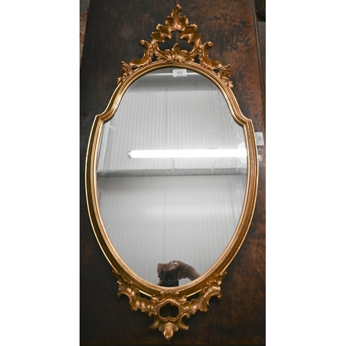 515 - Gilt-framed shield mirror with Rococo style crest and apron, 83 x 42 cm