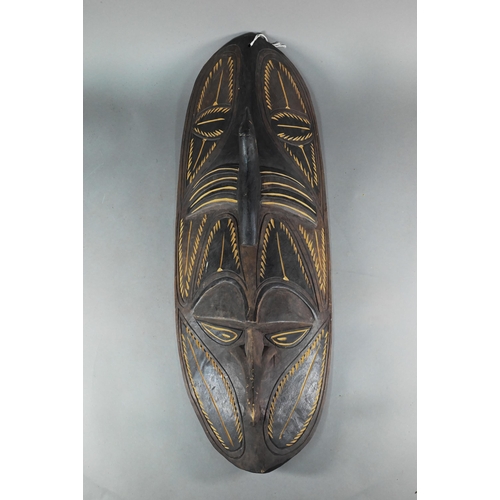 189 - A Papua New Guinea tribal carved wood shield, worked with a mask with prominent nose below a bird, 7... 