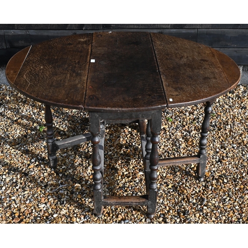 175 - An 18th century oak drop leaf dining table on gate-leg action turned supports